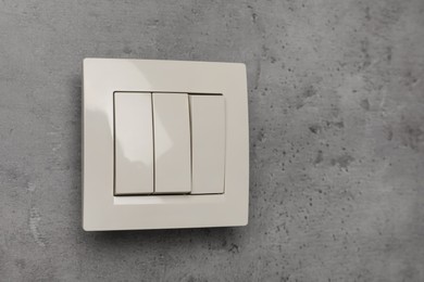 Photo of White light switch on grey background. Space for text