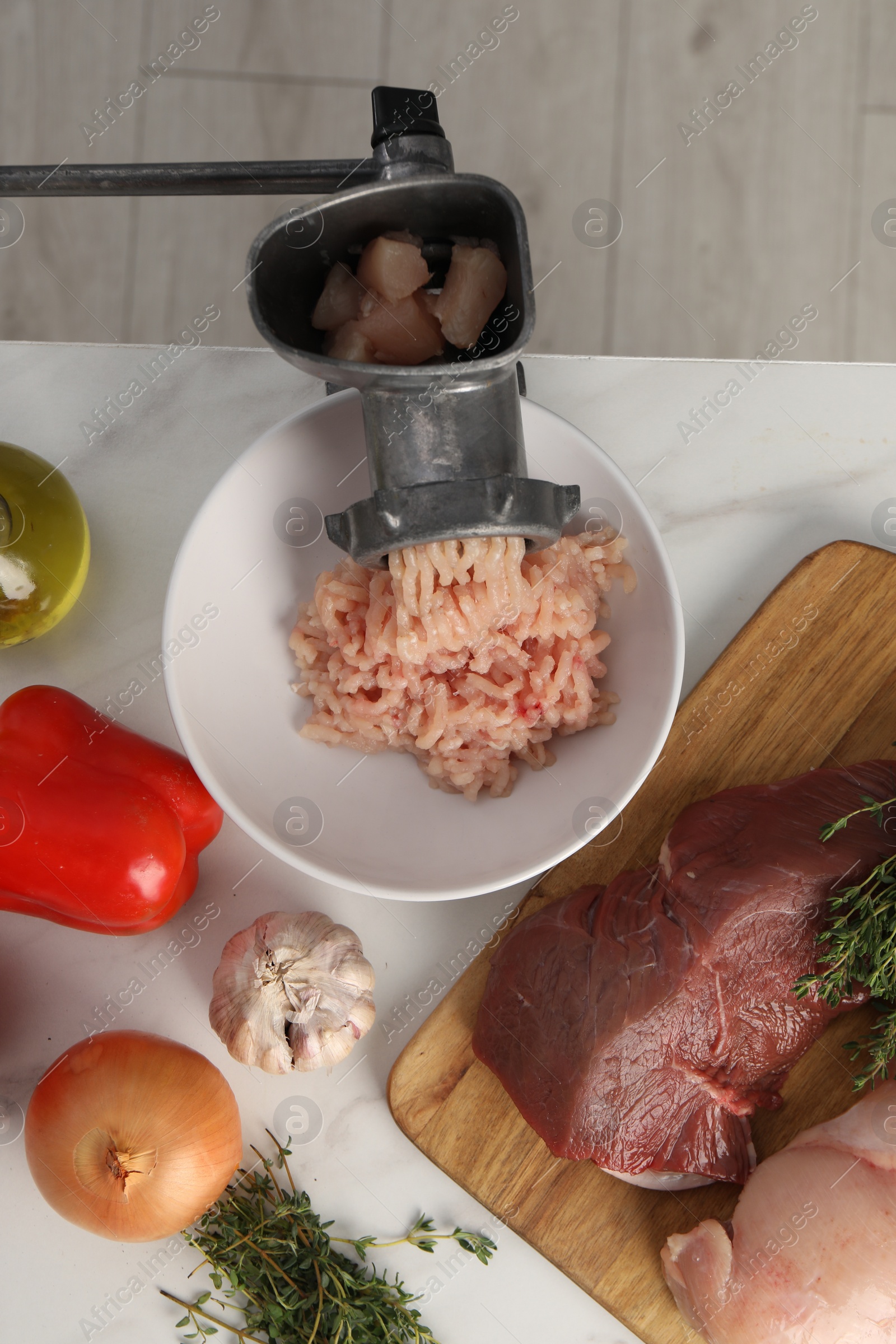 Photo of Metal meat grinder with chicken mince and products on white marble table, flat lay