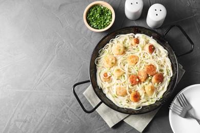 Photo of Delicious scallop pasta with green onion served on grey table, flat lay. Space for text