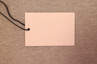 Photo of Cardboard tags on brown garment, top view. Space for text