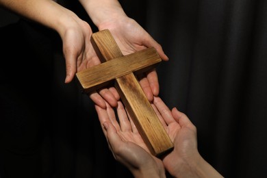 Photo of Easter - celebration of Jesus resurrection. Women holding wooden cross on dark background, closeup