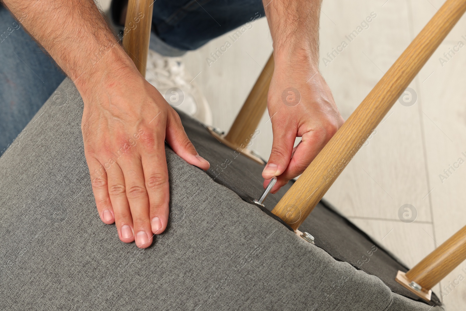 Photo of Man with hex key assembling armchair indoors, closeup