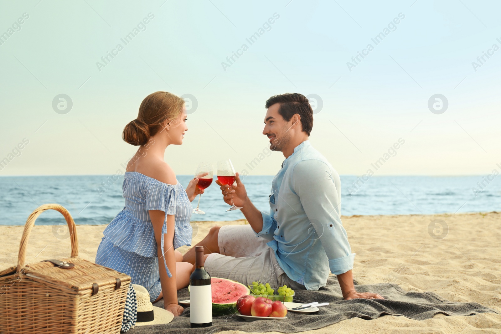 Photo of Beautiful young couple having picnic at sea beach