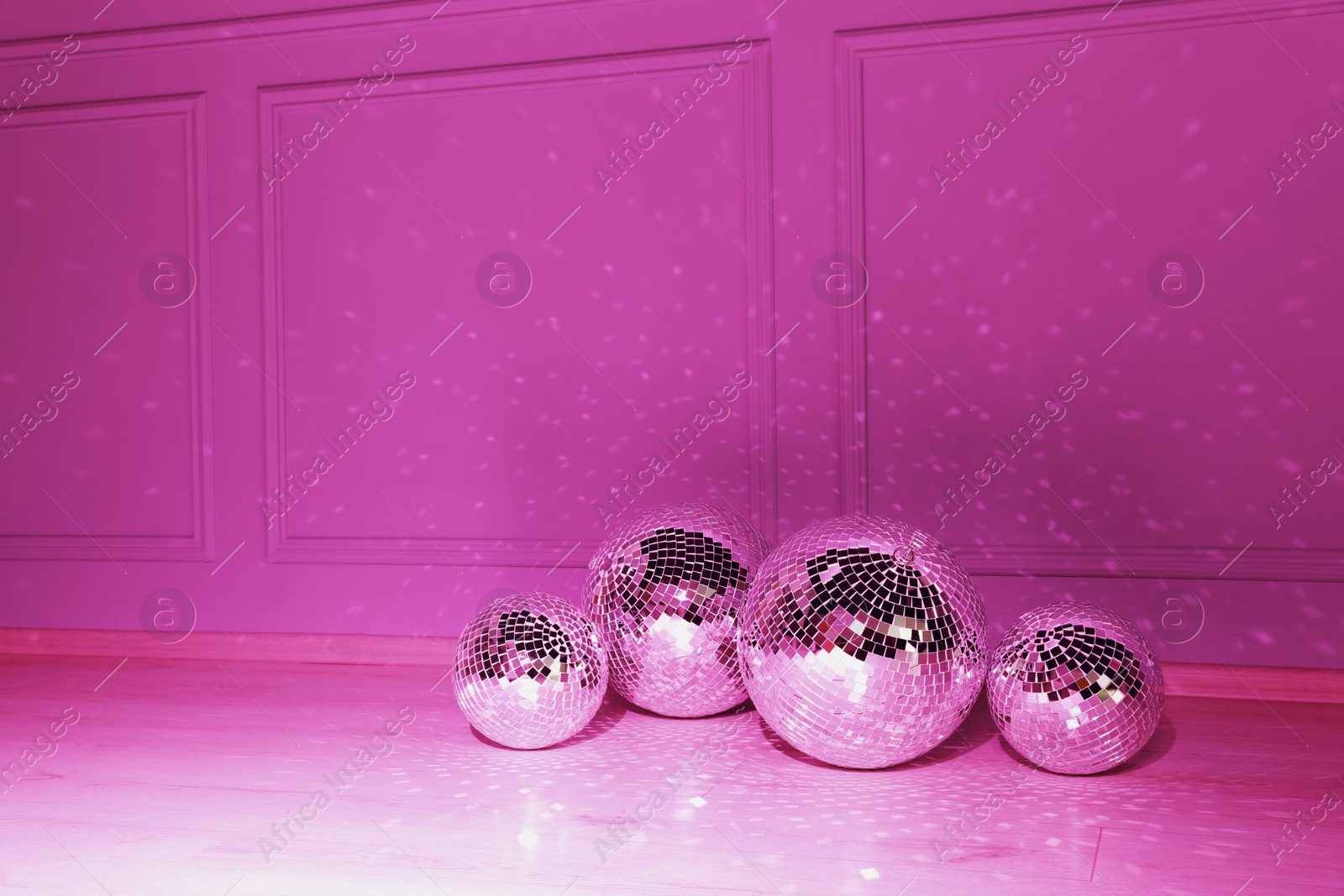 Photo of Shiny disco balls indoors, toned in pink. Space for text