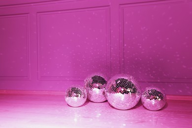 Photo of Shiny disco balls indoors, toned in pink. Space for text