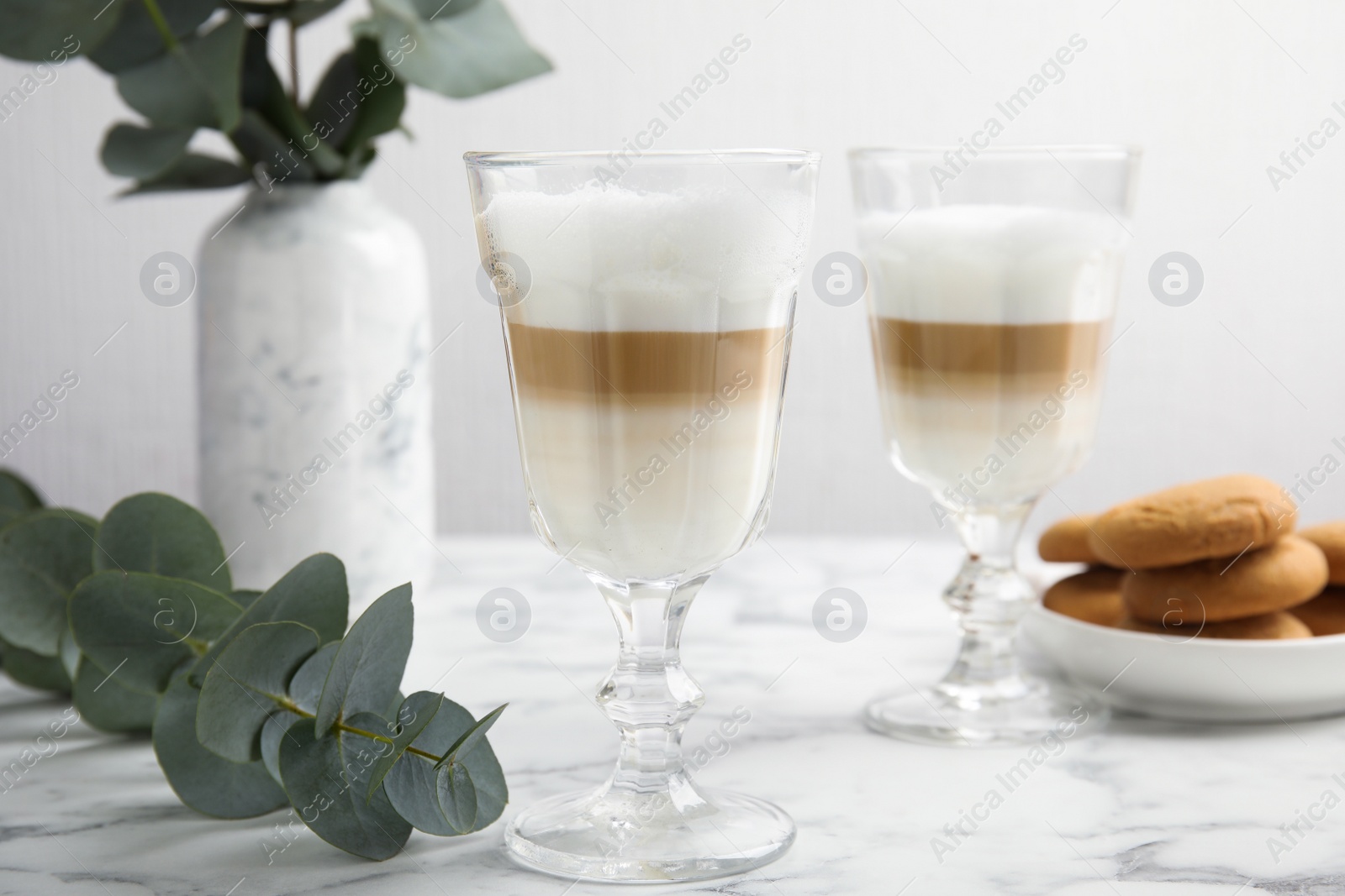 Photo of Delicious latte macchiato and tasty cookies on white marble table