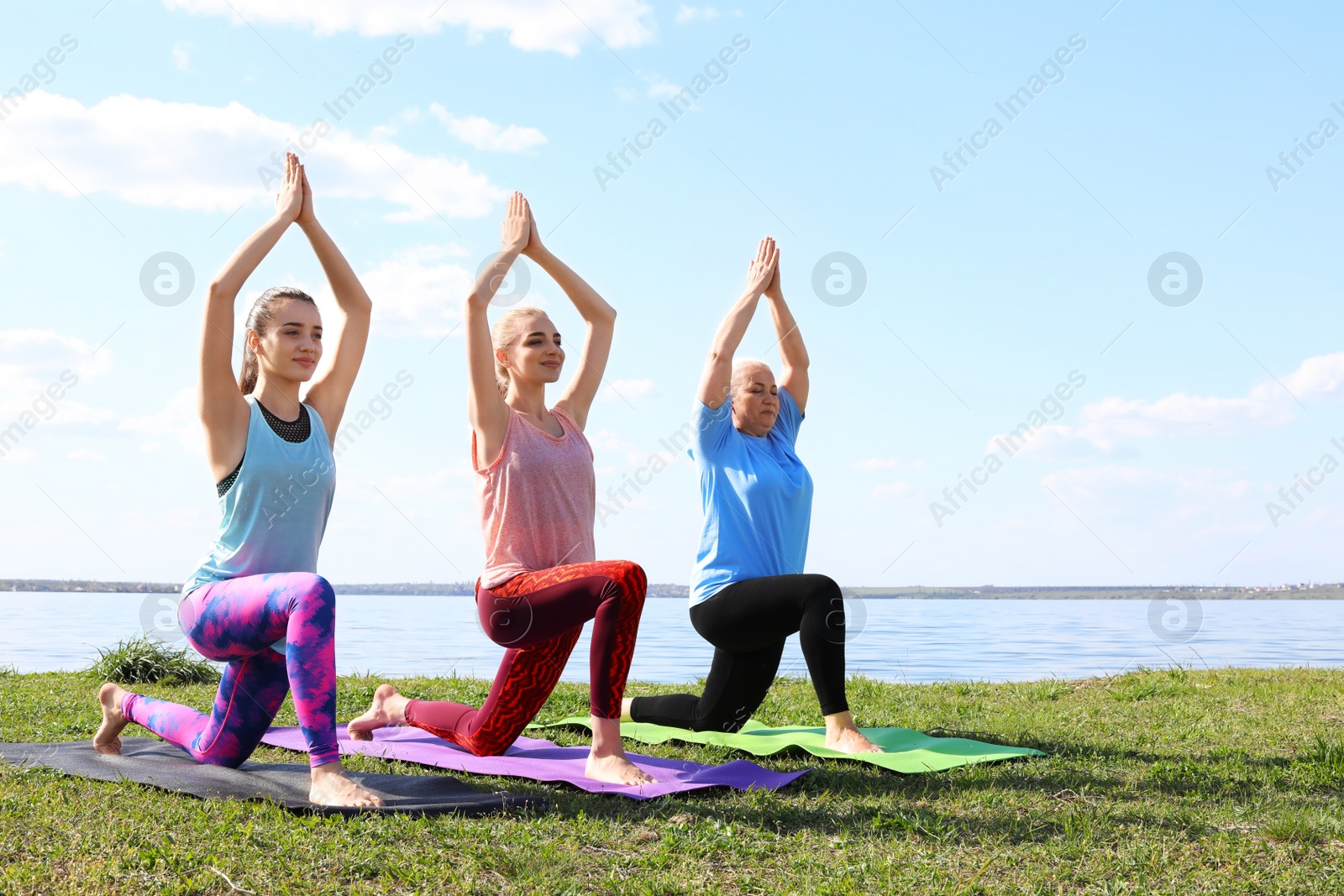 Photo of Group of women practicing yoga near river on sunny day