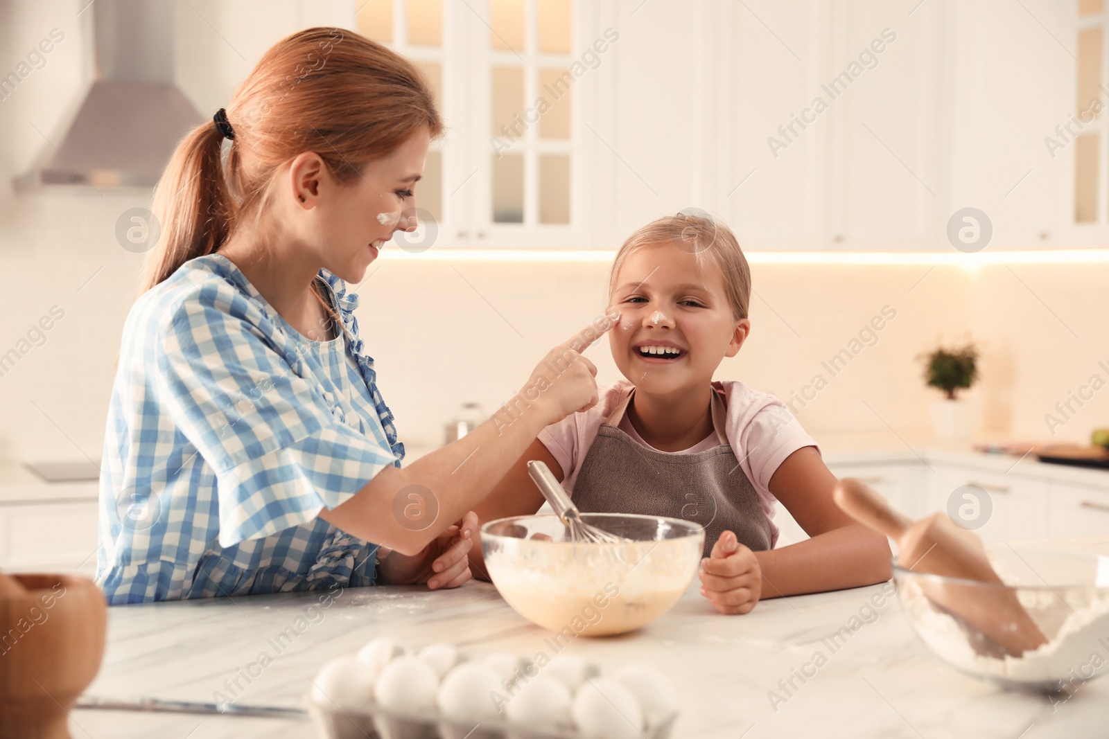 Photo of Mother and daughter making dough together in kitchen