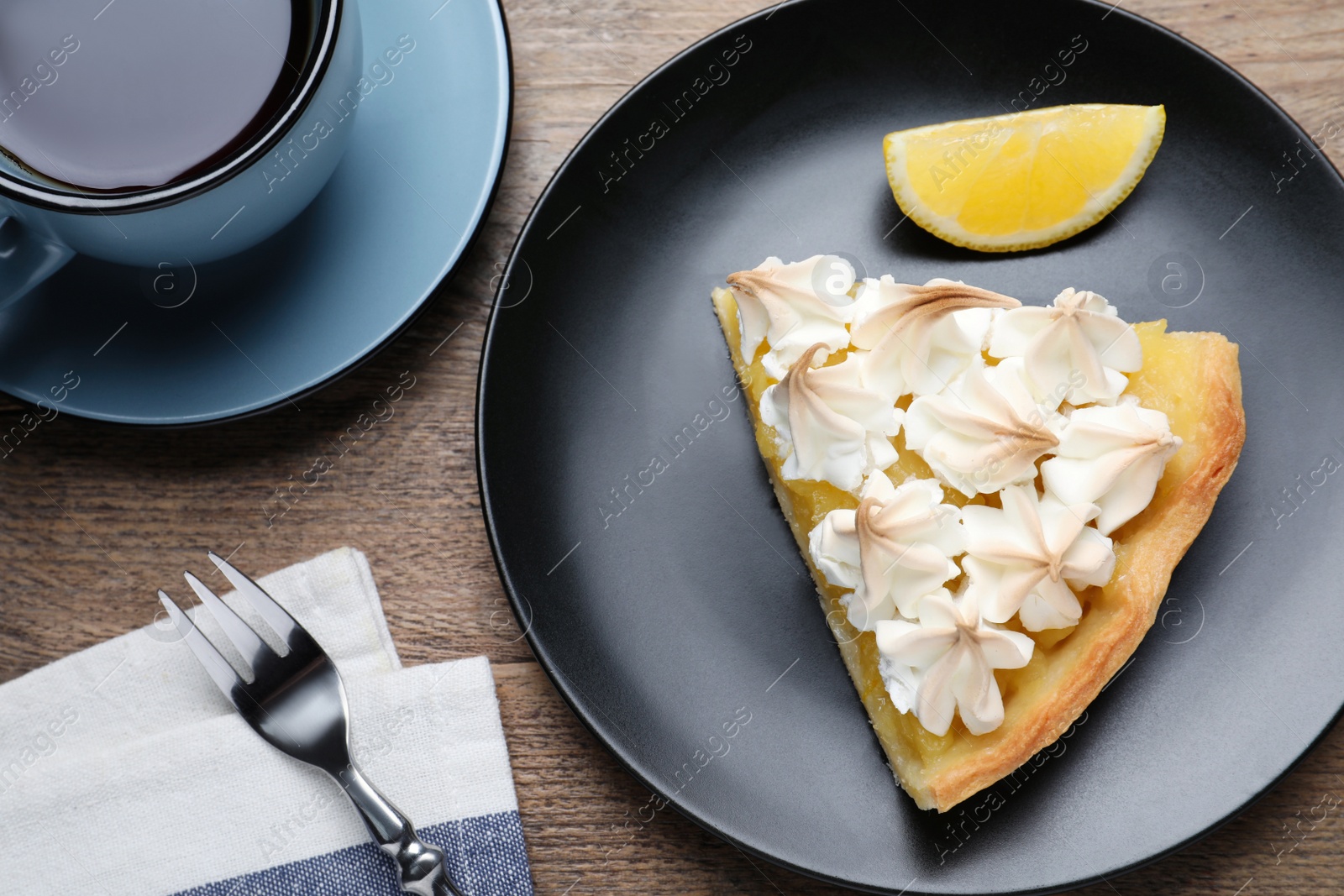 Photo of Piece of delicious lemon meringue pie served on wooden table, flat lay