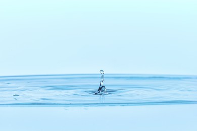 Photo of Splash of clear water with drop on light blue background, closeup