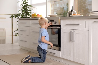 Photo of Little boy baking something in oven at home