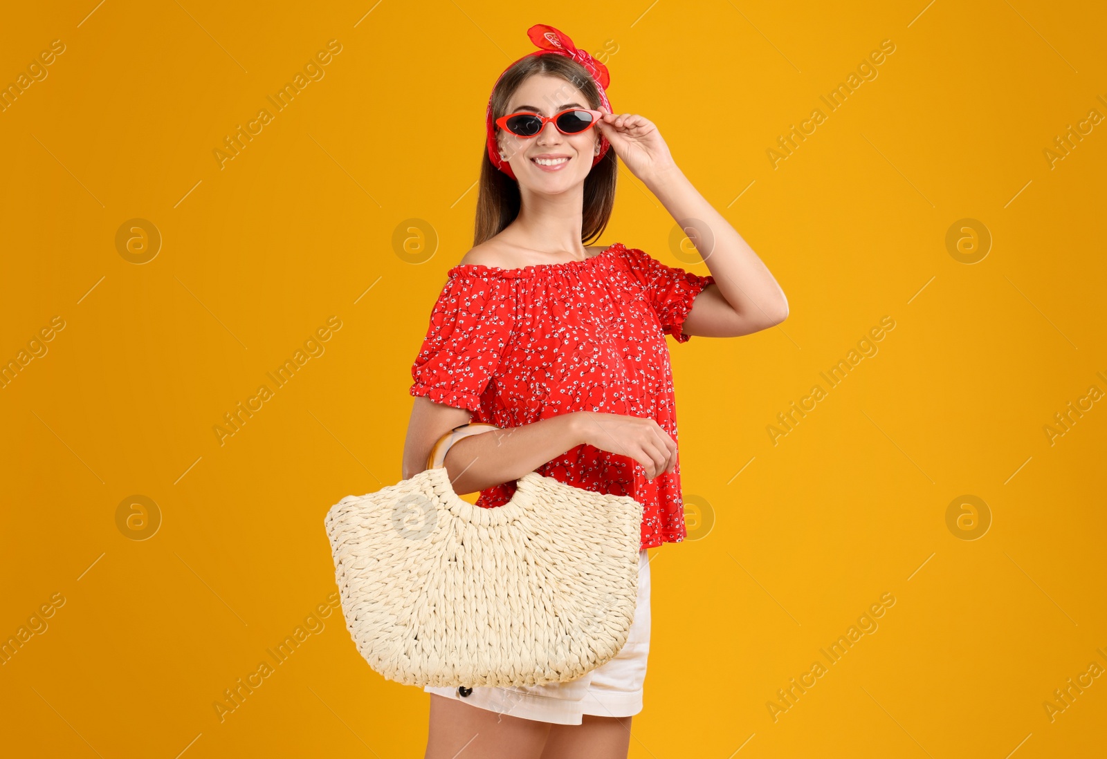 Photo of Beautiful young woman with stylish straw bag on yellow background