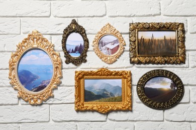 Photo of Vintage frames with photos of beautiful landscapes hanging on white brick wall