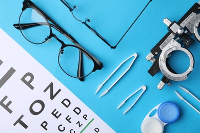 Photo of Flat lay composition with vision test chart and glasses on light blue background