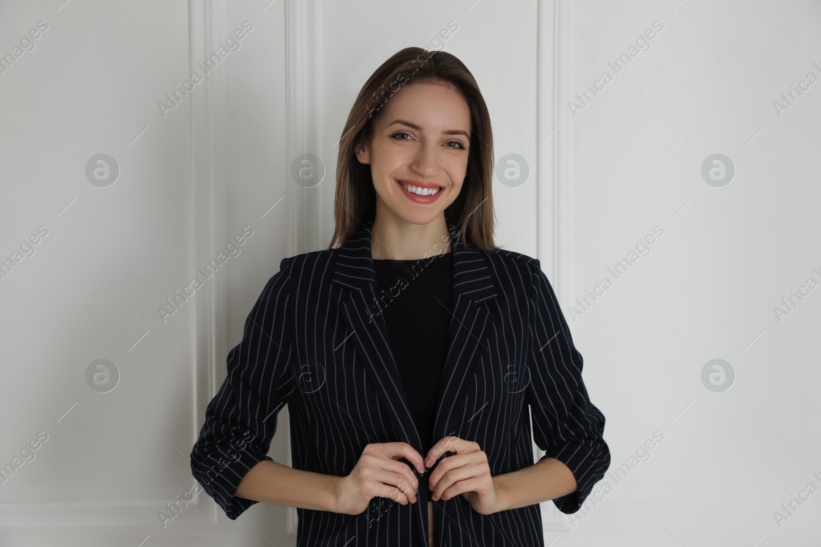 Photo of Portrait of beautiful young woman in fashionable suit near white wall. Business attire