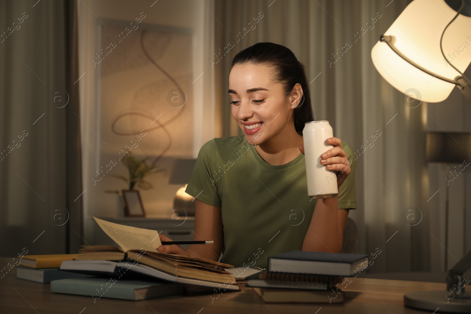 Photo of Young woman with energy drink studying at home