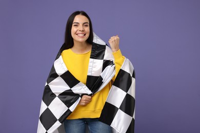 Happy young woman with checkered flag on violet background