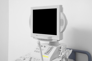Photo of Ultrasound machine near white wall, closeup. Medical equipment