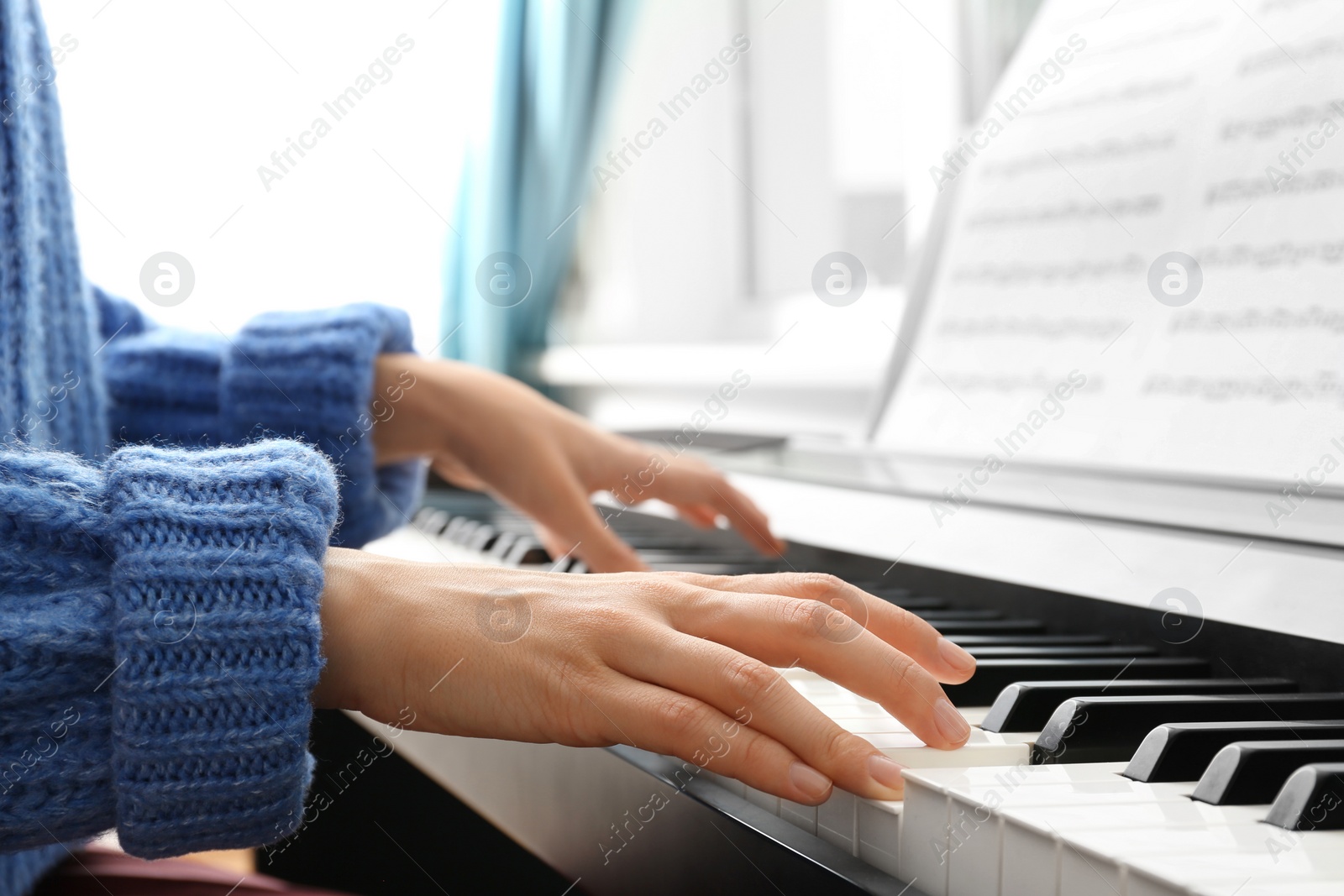 Photo of Young woman playing piano at home, closeup