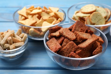 Photo of Different crispy rusks in bowls on light blue wooden table