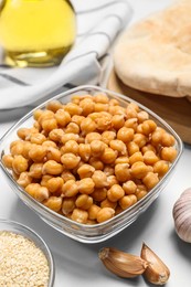 Photo of Delicious chickpeas and different products on white table. Hummus ingredients