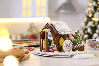 Beautiful gingerbread house decorated with icing on white table indoors