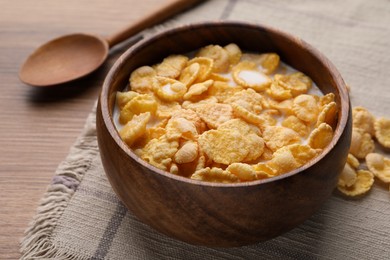 Photo of Tasty cornflakes with milk in bowl served on wooden table, closeup