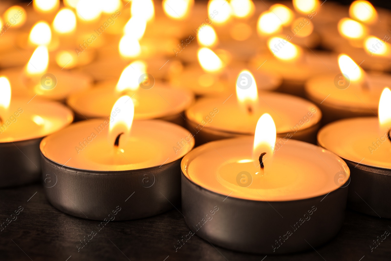 Photo of Many burning candles on table, closeup. Symbol of sorrow