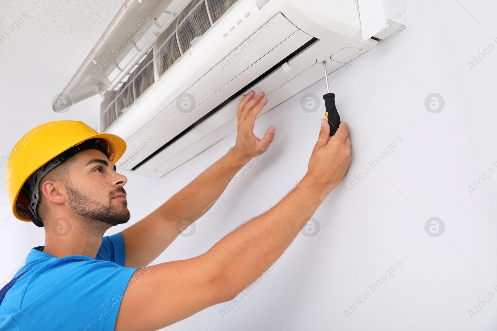 Photo of Professional technician maintaining modern air conditioner indoors