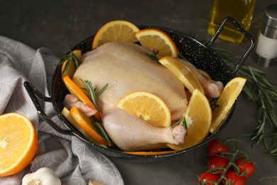 Photo of Chicken with orange slices and ingredients on grey table