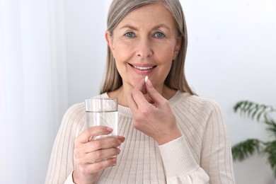 Photo of Beautiful woman taking vitamin pill at home