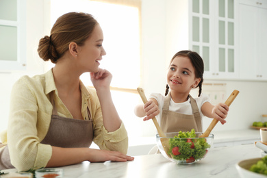 Mother and daughter cooking salad together in kitchen