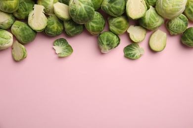 Photo of Fresh Brussels sprouts on pink background, flat lay. Space for text