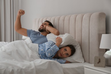 Young couple suffering from noisy neighbours in bed at home