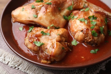 Tasty cooked rabbit meat with sauce and parsley on table, closeup