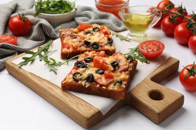 Tasty pizza toasts and ingredients on white table