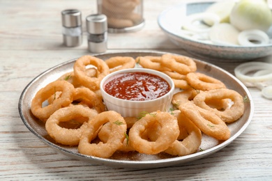 Fried onion rings served with sauce on plate