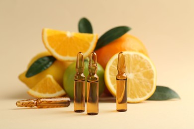 Photo of Skincare ampoules with vitamin C, different citrus fruits and leaves on beige background