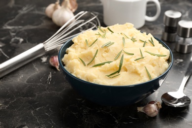 Photo of Bowl with tasty mashed potato on dark table