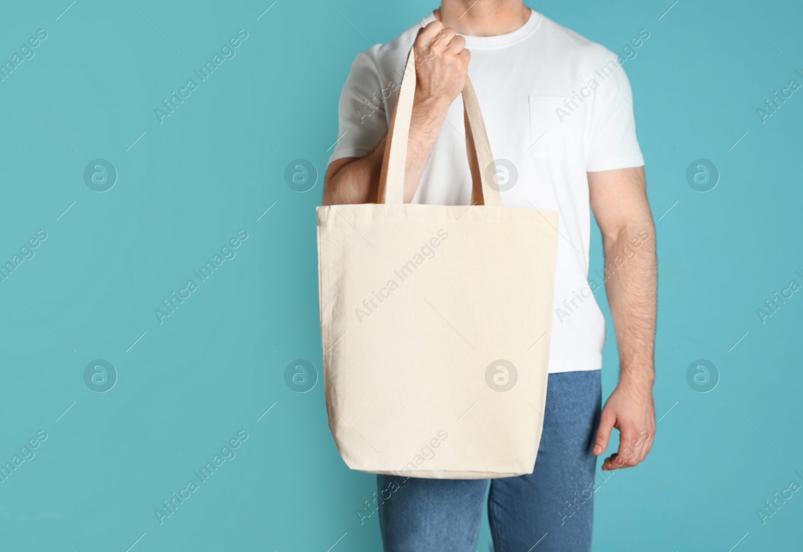 Photo of Man with cotton shopping eco bag on color background. Mockup for design