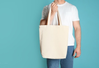 Photo of Man with cotton shopping eco bag on color background. Mockup for design