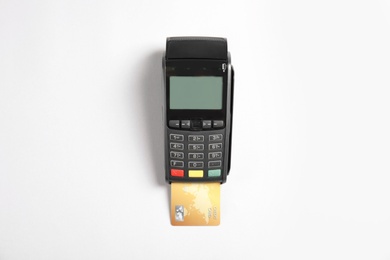 Photo of Modern payment terminal with credit card on white background, top view