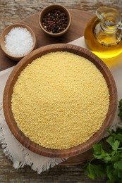 Raw couscous and ingredients on wooden table, flat lay