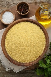 Photo of Raw couscous and ingredients on wooden table, flat lay