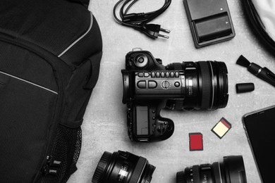 Professional photography equipment and backpack on grey stone table, flat lay