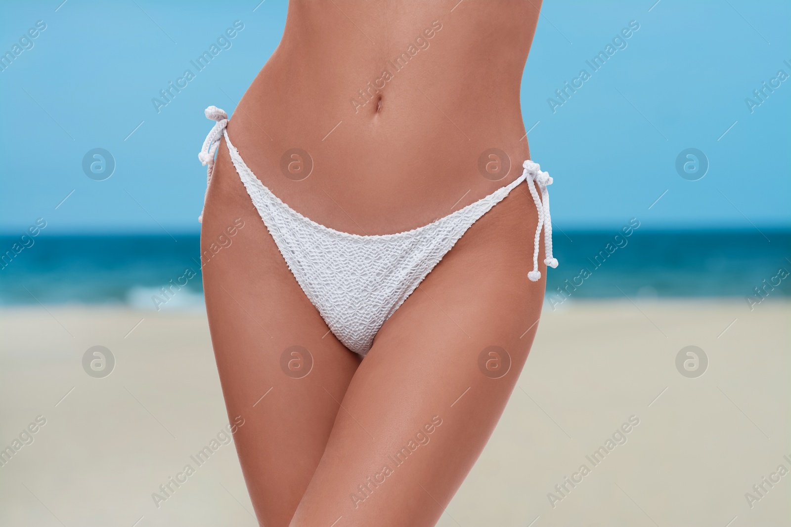 Image of Woman in stylish white bikini on sandy beach near sea, closeup