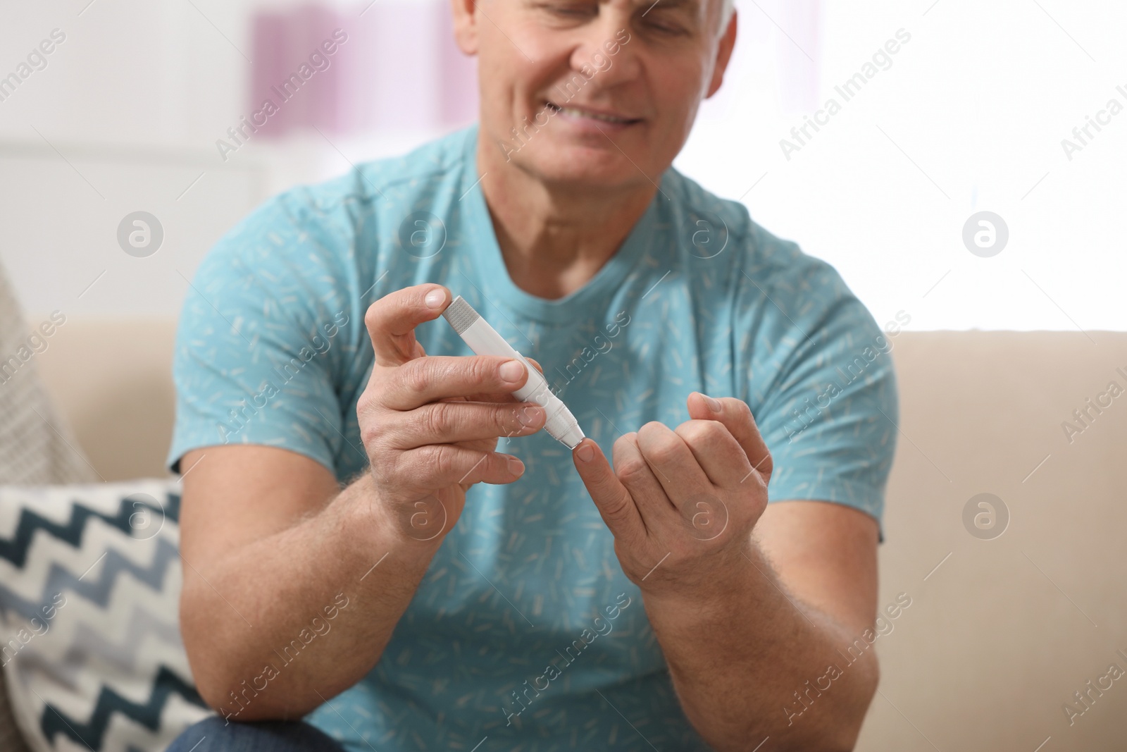 Photo of Senior man using lancet pen at home, closeup. Diabetes control