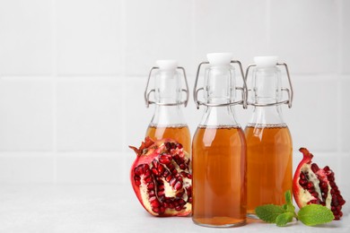 Photo of Tasty kombucha, pomegranate and mint on white table, space for text