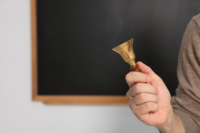 Photo of Teacher with school bell near black chalkboard, closeup. Space for text