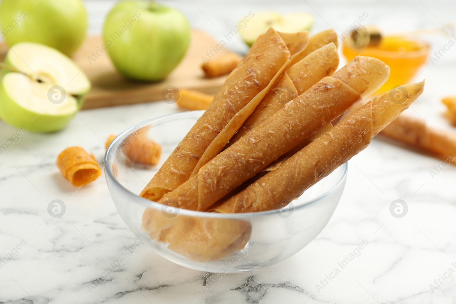 Photo of Delicious fruit leather rolls on white marble table, closeup